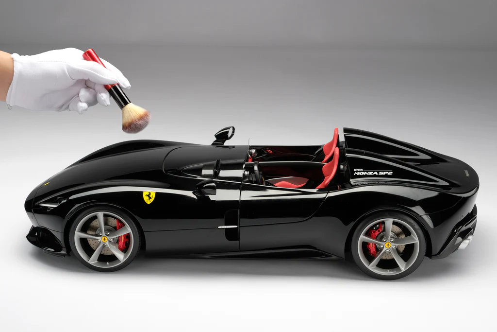 Person dusting off a model car from Amalgam Models